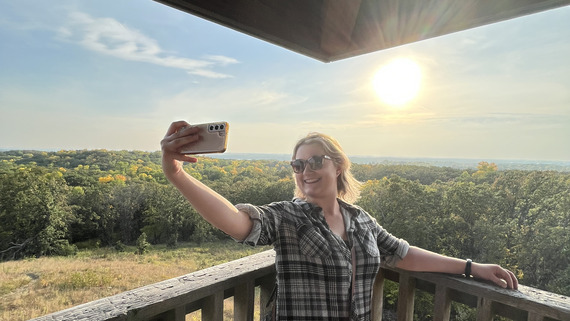 A person takes a selfie on a beautiful sunny, fall day from an overlook. 