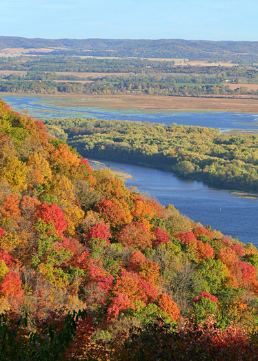 Looking out over a river valley with bright trees and a calm river below. 