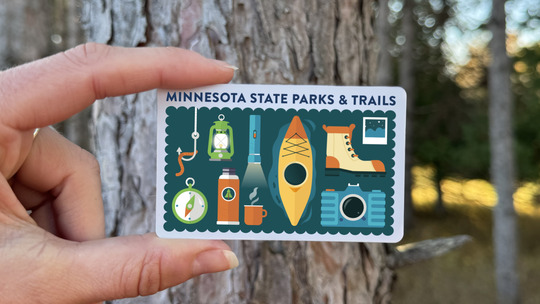 A hand holds a Minnesota state parks and trails gift card.