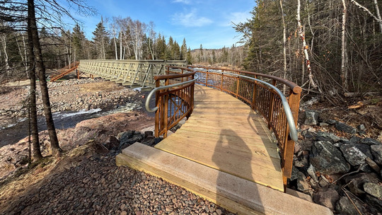 A brand new construction of sturdy wood and steel crosses a small river. 