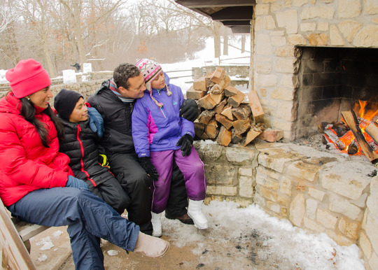 A family sits by a bonfire in winter. 