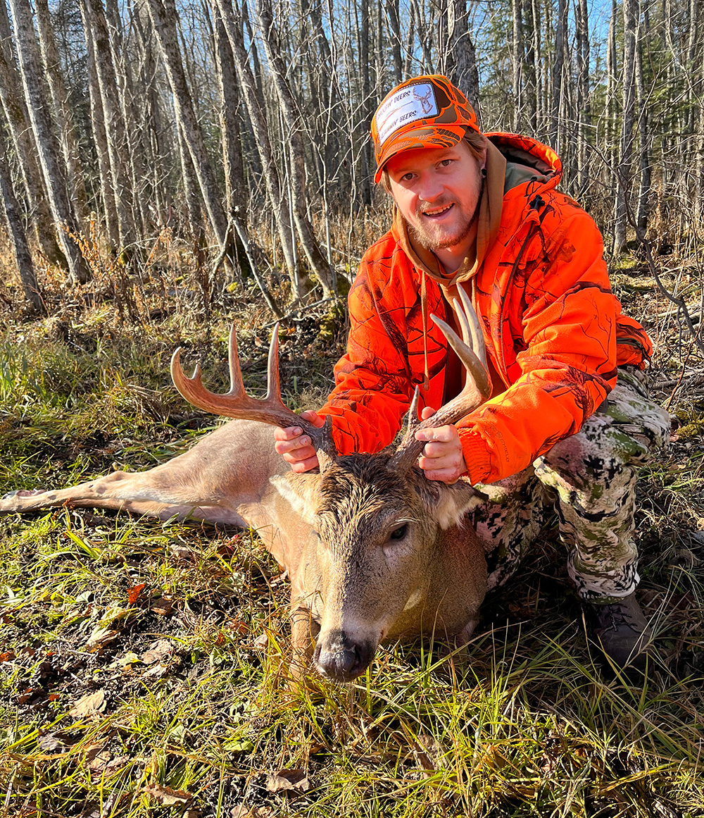 hunter in blaze orange with a nice buck he harvested
