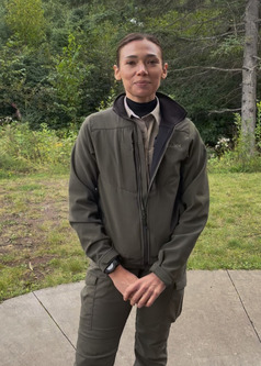 Marcie, a park ranger stands in uniform outside a DNR building. 