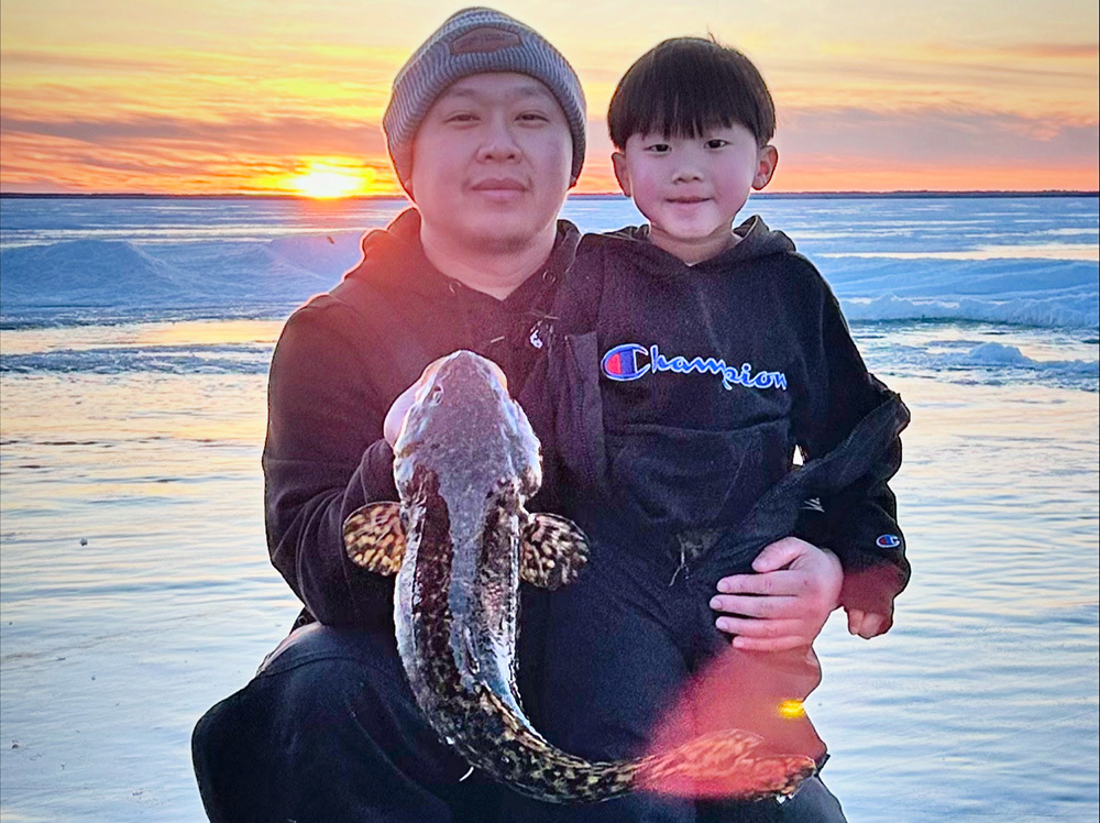 angler and kid holding a burbot caught ice fishing