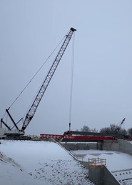 A crane lowers bridge girders on a snowy day. 