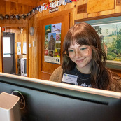 A front desk worker smiles while at a computer. 