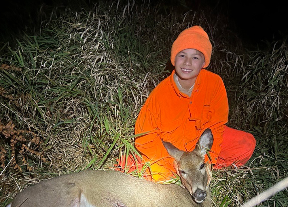 young hunter with a doe he harvested