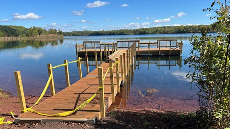 A brand new fishing pier on a calm, blue lake. 