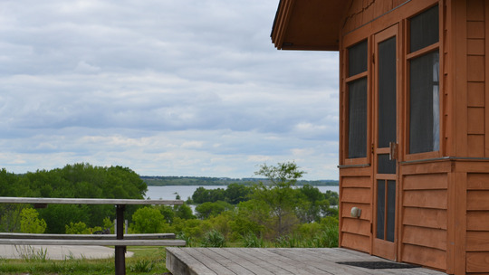 A camper cabin next to a sweeping view to a lake on a calm, summer day.