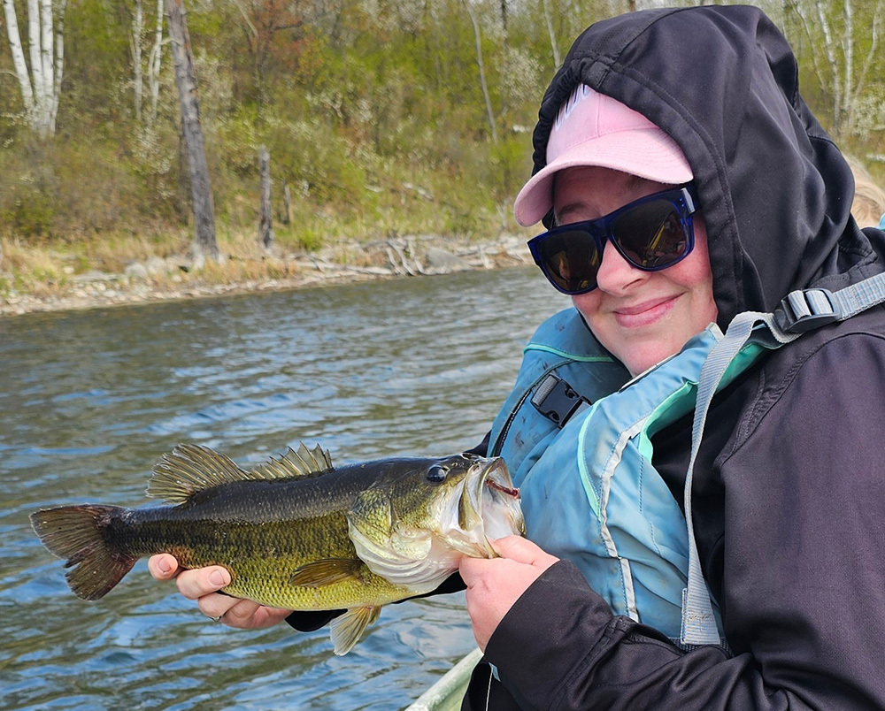 angler with a bass caught with angler looking bundled up on a cool day