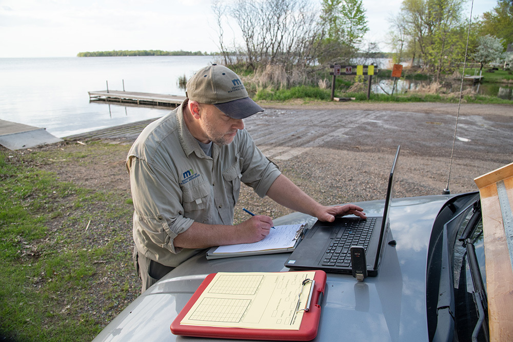 a creel clerk entering data during a creel survey at a lake access