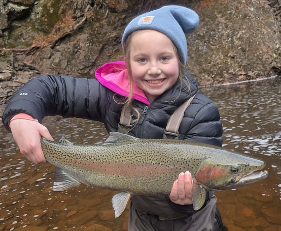 Young girl with big smile holding her first steelhead ever caught on the North Shore, Minnesota