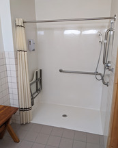 A shower area features a fold-down bench, detachable spraying water head, and seamless tile gap into the shower area.