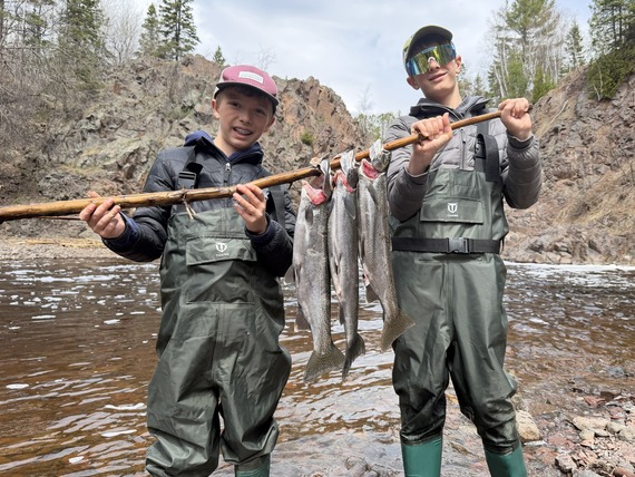 Two happy young anglers holding three clipped steelhead harvested in a North Shore river