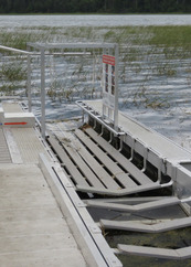 A dock section has a narrow ramp attached to the side where kayaks can pull up level to the dock.