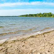 A bright, sandy beach along a crystal clear lake. 