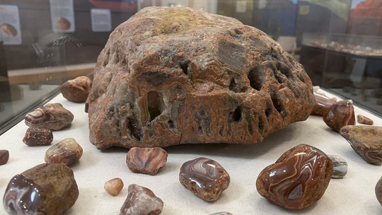 A display case holds a huge Lake Superior agate surrounded by smaller polished agates.