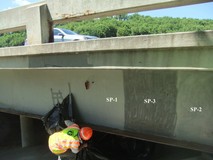 Crew member inveistigates surface prep conditions on a section of steel beam before coatings are applied.