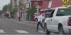 Woman is crossing the street on a city crosswalk.