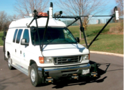 The digital pavement inspection vehicle is a large white van with a mounted rig of instrumentation extending over the front