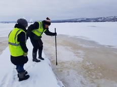 Research team collecting water sample through icy water.