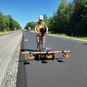 A worker pushing a profiling density system along new pavement