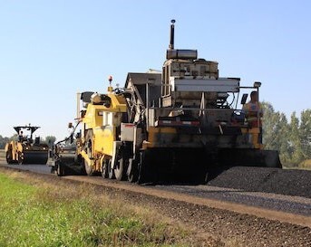 Asphalt roller compacts new pavement on rural road