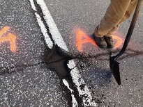 Maintenance worker repairs a pothole on a rural road