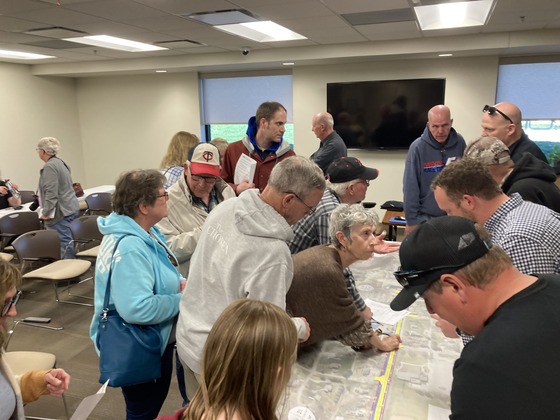 Photo of people looking at a construction map of Highway 57 in Mantorville and discussing it.