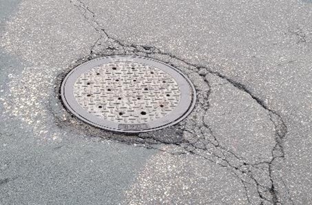 Manhole in distressed pavement