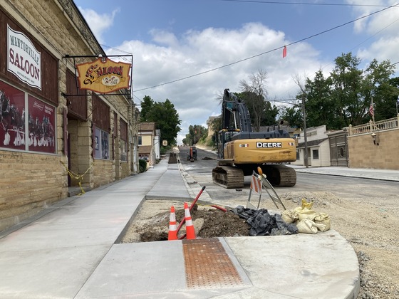 Photo of construction site on Highway 57 in Mantorville with an excavator on a paved street.