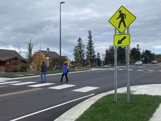 Pedestrians crossing intersection marked with signage for crossing