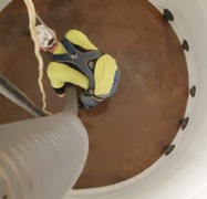 A Rochester Public Works staff member cleans sediment from a brine storage tank.