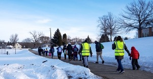 Grade school students walking to school on snowy sidewalk