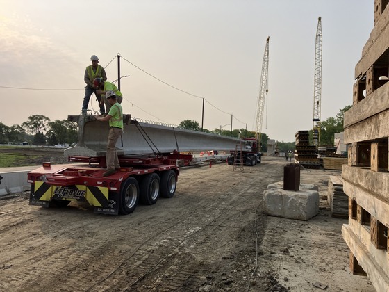 Truck backs up with bridge beam on Highway 52 for placement over Interstate 90.