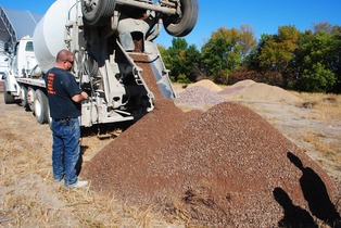 Man stands and monitors permeable barrier material unload from a cement truck.