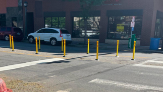 Yellow pedestrian safety bollards delineate a protected pedestrian zone on a roadway.