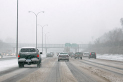 Motor vehicles travel on a slushy roadway.