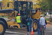 Residents viewing and climbing into a large yellow bulldozer