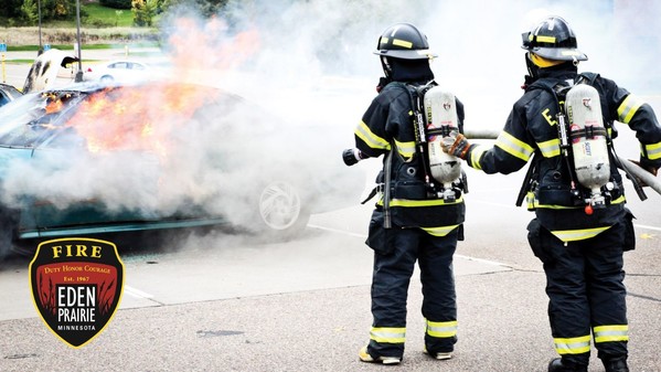 Two firefighters work together to put out a fire