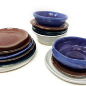 3 piles of glazed ceramic plates and bowls