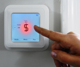 A woman points to an electronic thermostat 