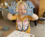 Little girl holding up two hands that have paint