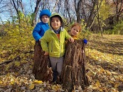 Three preschool children playing outdoors during the fall