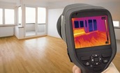A person uses a device to measure heat levels in a home