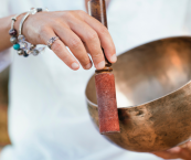 Hand holding up a metal singing bowl during a Sound Bath session