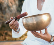 Closeup of a person holding a metal bowl during a sound bath session