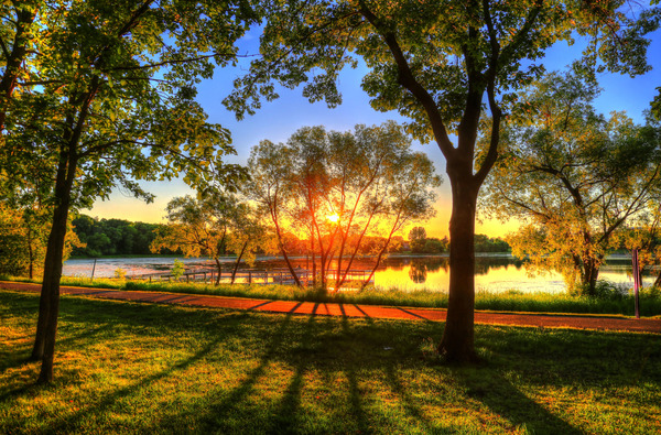 Sun rising or setting at Round Lake Park, view of large trees and lake