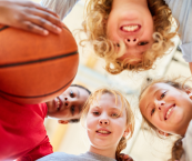Group of kids huddled in a circle, one is holding a basketball
