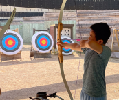 Kid aiming arrow at a target at the archery range